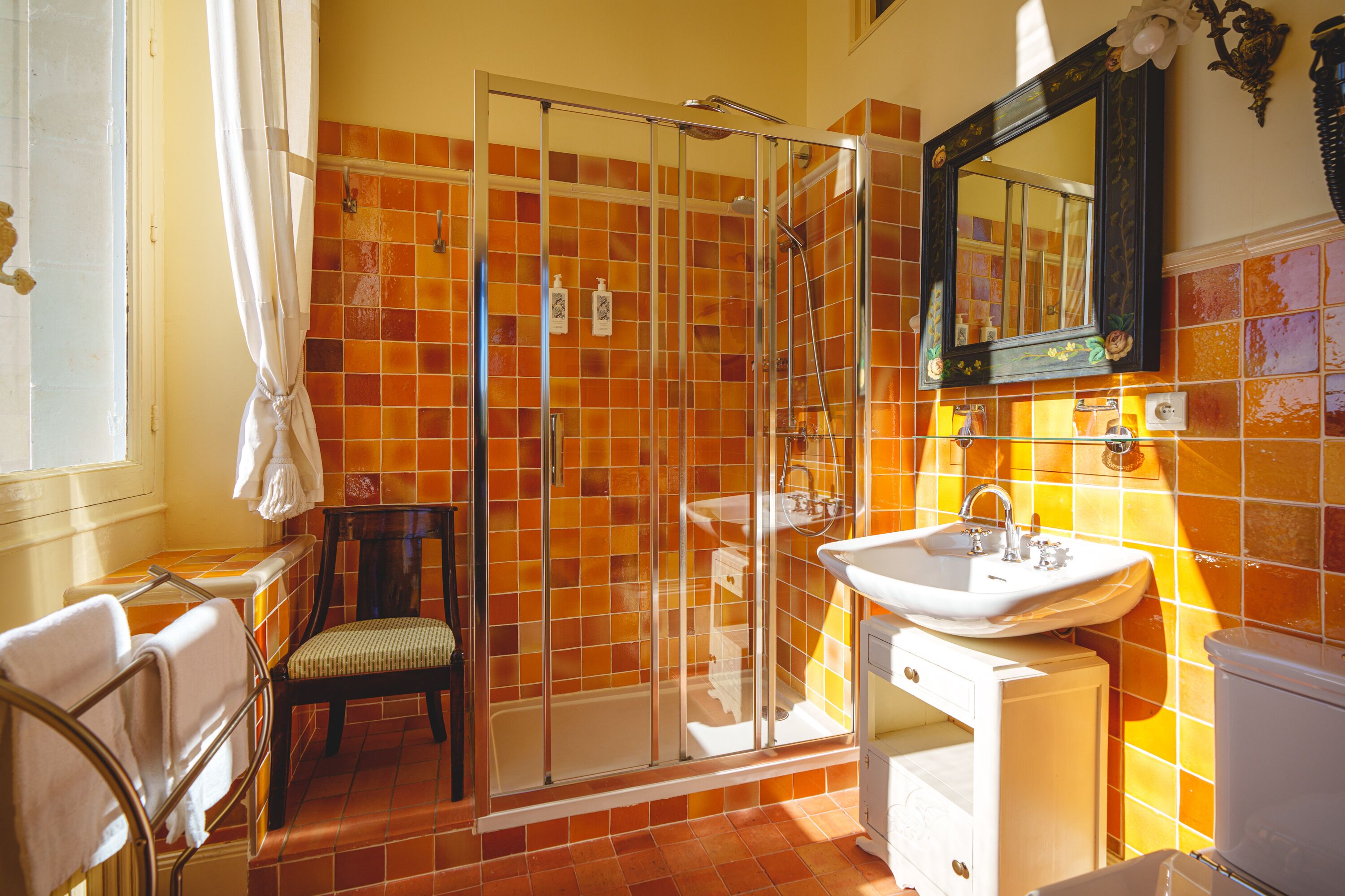 A bathroom with a glass shower enclosure, a white sink, and a mirror above it.