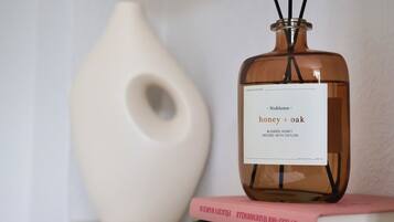 A bottle of fragrance diffuser with a label reading "Noblesse honey + oak" on top of a stack of books.