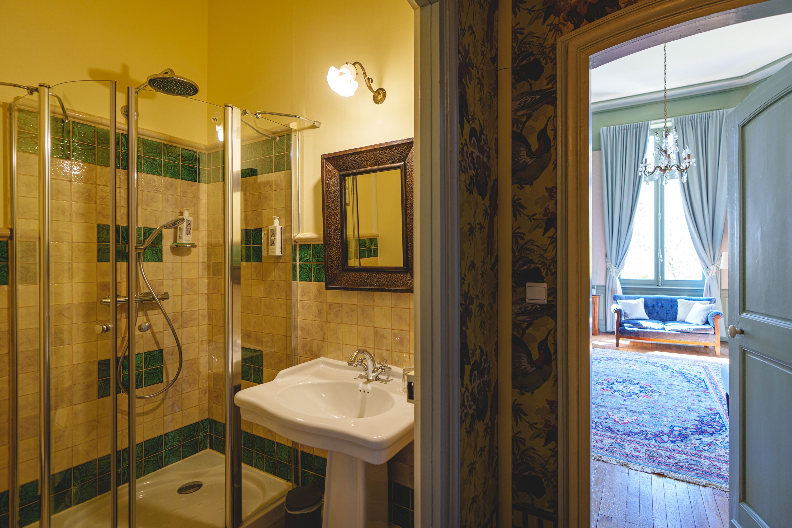 A bathroom with a glass-enclosed shower, a sink, and a mirror.