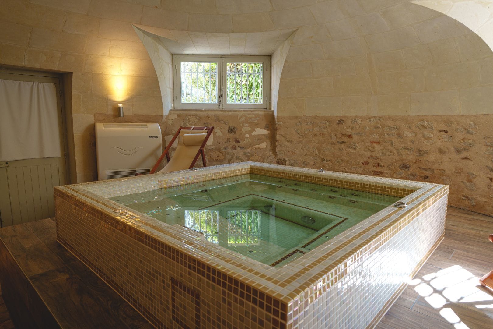 A room with a large tiled hot tub, a window with bars, and a radiator.