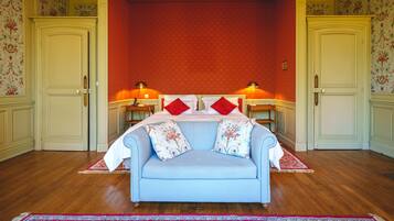 Ein Schlafzimmer mit einem blauen Sofa, einer Wand mit rotem Muster und zwei Nachttischen mit Lampen.