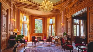 Una sala imponente con paneles de madera decorados, un candelabro y un ventanal con cortinas.