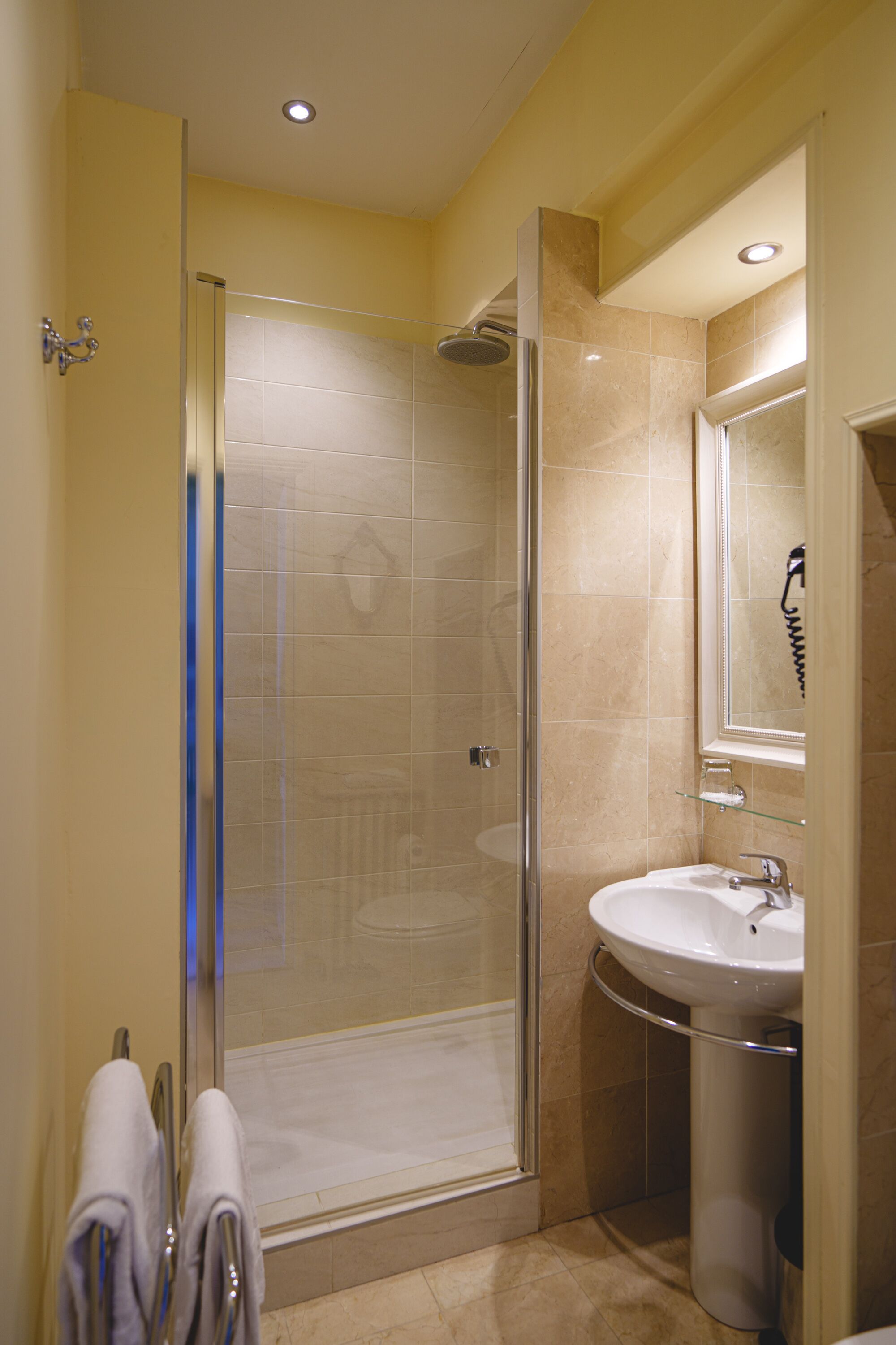 A bathroom with a glass-enclosed shower, a sink, and a mirror.