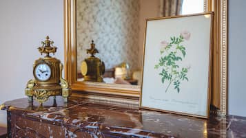 A marble table with a framed botanical print and a decorative clock.