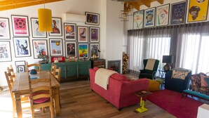 Ein geräumiges Wohnzimmer mit einem Holzesstisch, einem roten Sofa und einem farbenfrohen Teppich.