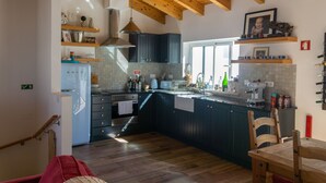 Eine Küche mit Holzbalken, dunklen Schränken, einem Edelstahl-Kühlschrank und einem Holzessttisch.