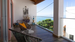 Un balcon avec des fauteuils en osier, une petite table et une plante en pot.
