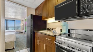 Ein Hotelzimmer mit Küchenzeile, inklusive Kühlschrank, Mikrowelle, Herd und Spüle.