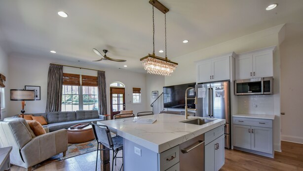 A modern kitchen with a central island, white cabinetry, stainless steel appliances, and a ceiling fan. - Welcome to Tide on 12th! (Tuscaloosa)