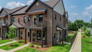 A two-story brick house with a balcony, large windows, and a well-maintained lawn. - Welcome to Tide on 12th! (Tuscaloosa)