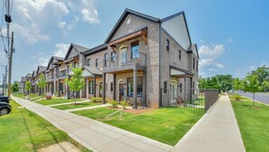 A row of modern brick townhouses with balconies, a paved driveway, and a well-maintained lawn. - Welcome to Tide on 12th! (Tuscaloosa)