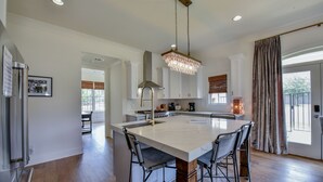 A spacious kitchen with a large island, modern appliances, and a chandelier. - Welcome to Tide on 12th! (Tuscaloosa)