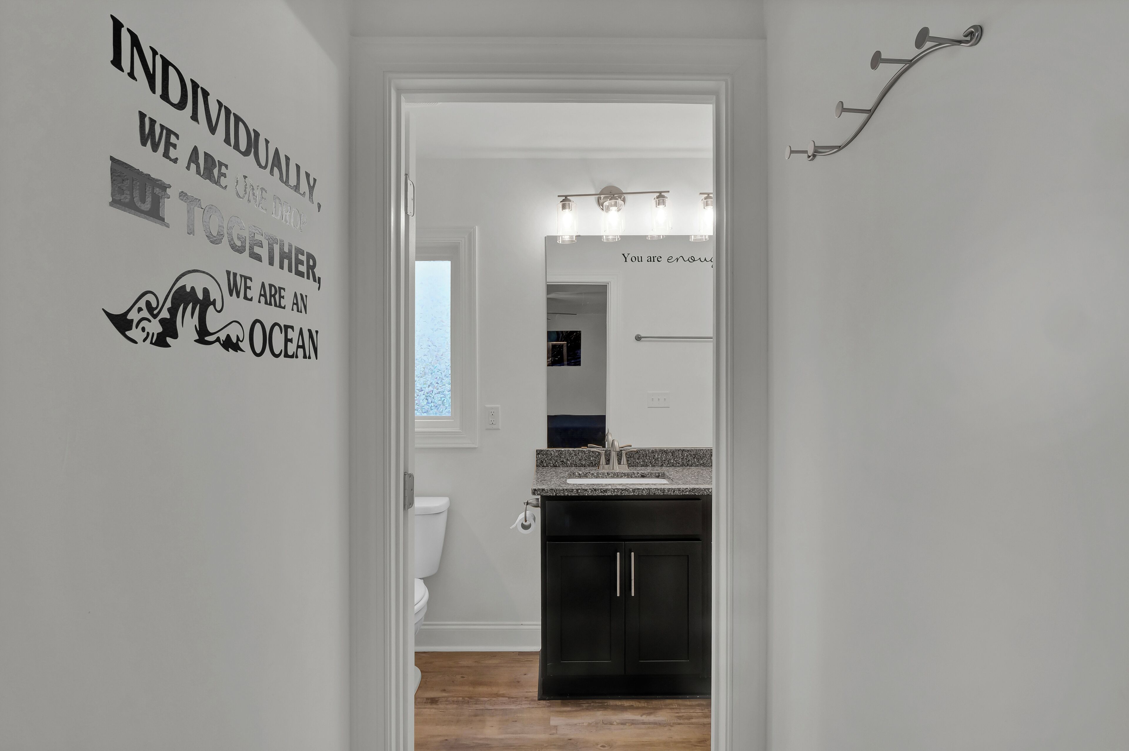 A modern bathroom with a vanity, mirror, and a wall-mounted light fixture.