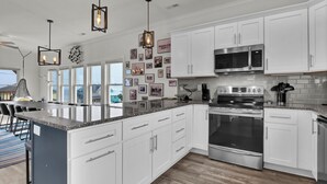 Una cucina moderna con mobili bianchi, elettrodomestici in acciaio inossidabile e un'isola grande.