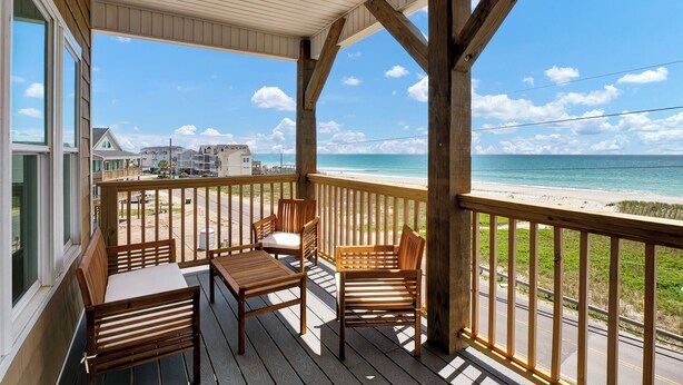 Un terrazza in legno con mobili da esterno che si affaccia su una spiaggia.