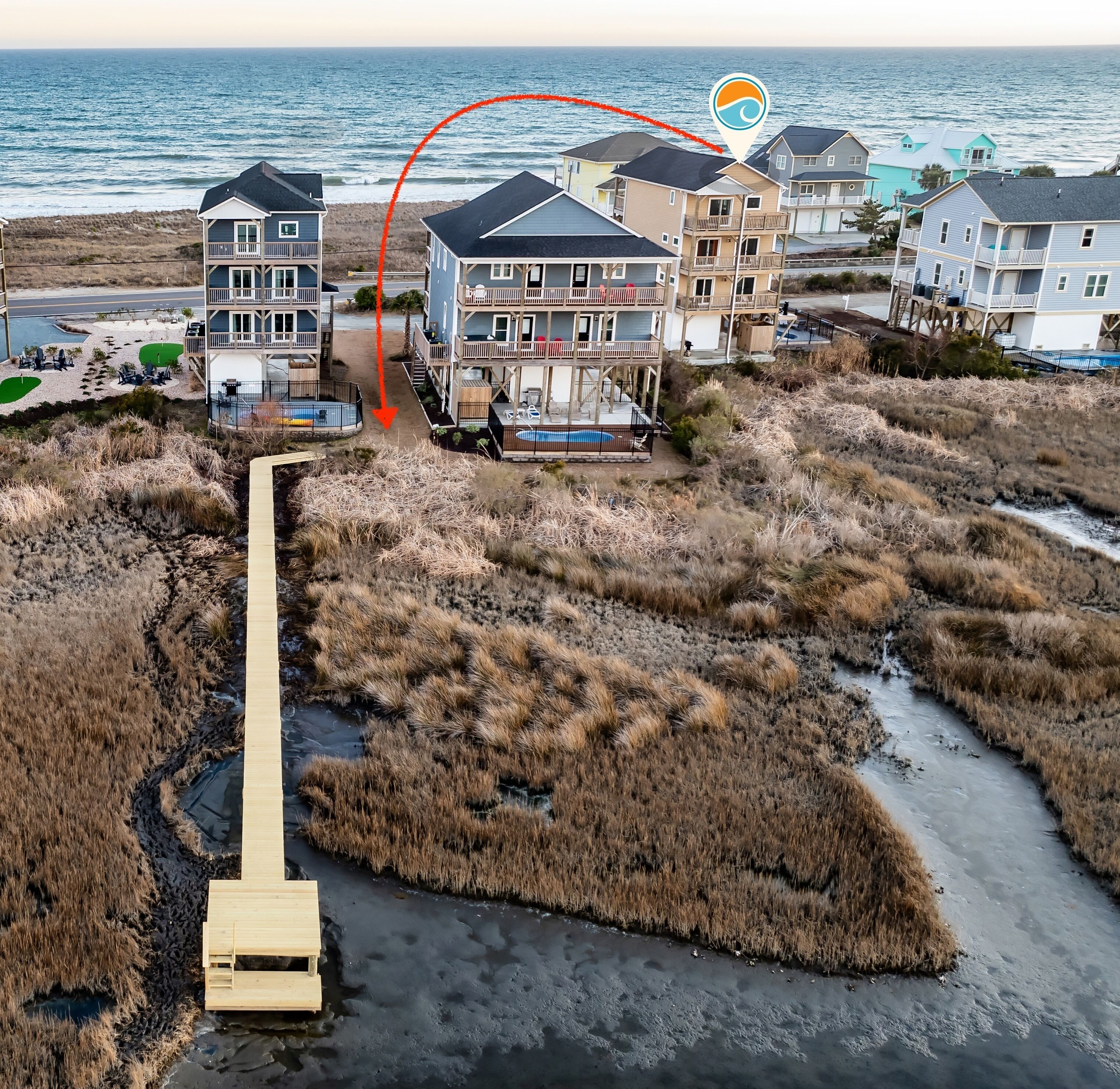 Une propriété située en bord de mer, comprenant plusieurs bâtiments, une piscine et une promenade qui mène à la plage.