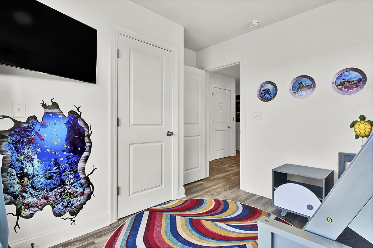 A room with a large aquarium, white doors, a colorful striped rug, and three wall-mounted pictures.
