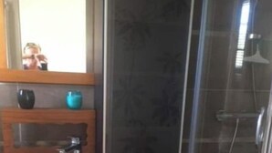 Une salle de bain avec un lavabo blanc, un miroir et une douche.
