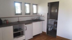 Une cuisine de taille réduite avec des meubles blancs, un plan de travail en bois et une fenêtre au-dessus de l’évier.