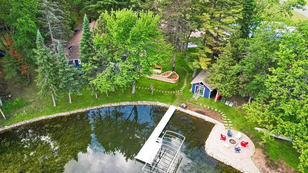 An aerial view of a property with a swimming pool, a small dock, and a garden area with a blue house and red chairs. - Spacious Cabin on Whitefish Chain—Perfect for  Family Vacations! (Crosslake)