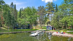 A lakeside cabin with a dock, surrounded by dense forest and a small shed. - Spacious Cabin on Whitefish Chain—Perfect for  Family Vacations! (Crosslake)