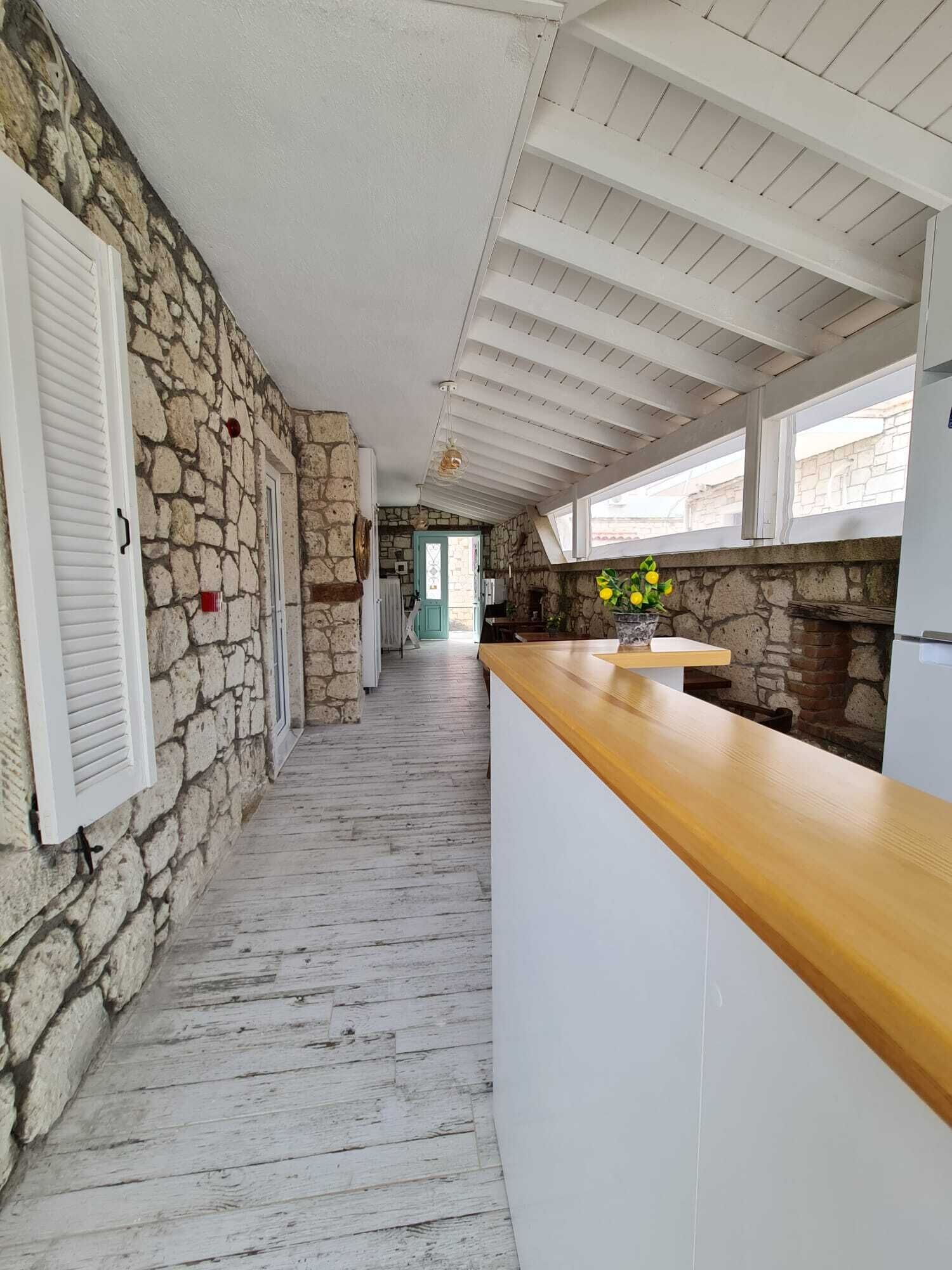 Una cocina con paredes de piedra, encimera de madera y vistas a través de una puerta.