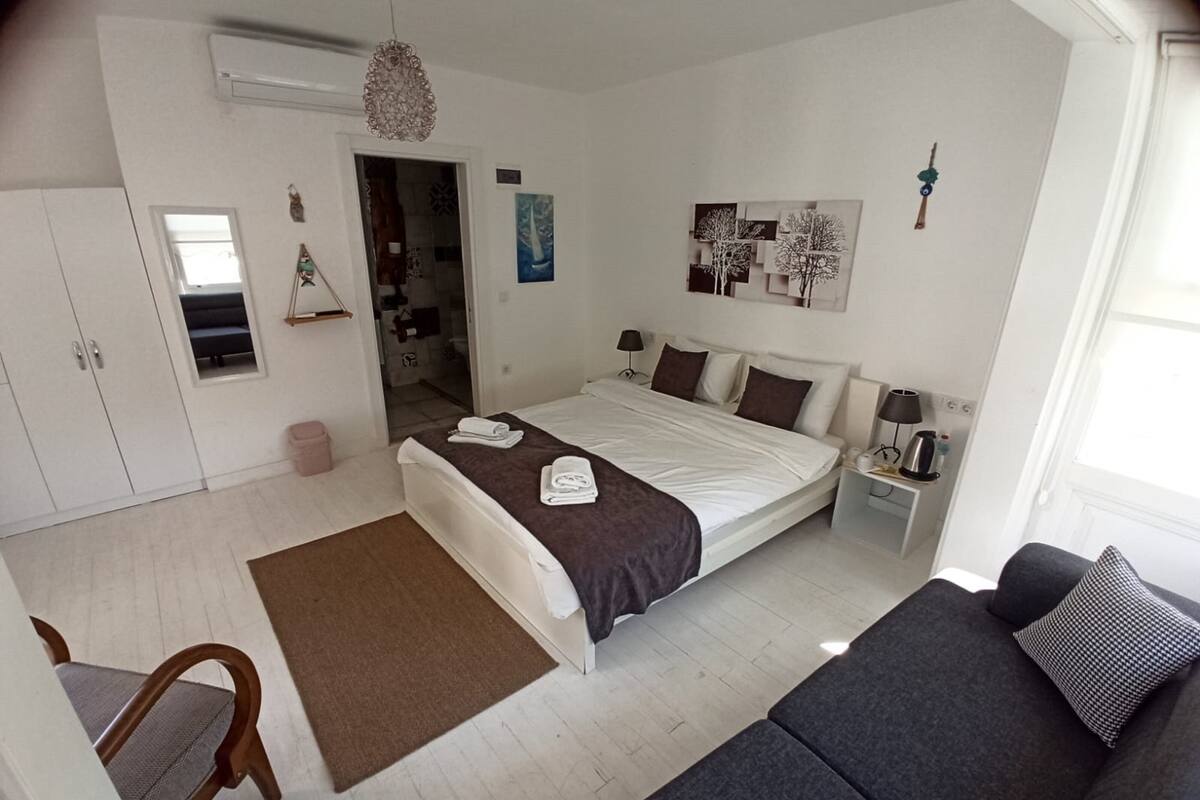 A modern bedroom with a large bed, a sofa, a desk, and a wardrobe.