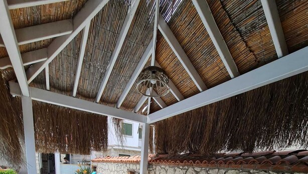 A covered outdoor area with a pool, lounge chairs, and a stone wall. - Nidus Alaçatı  (Cesme)