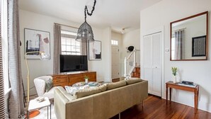 Un salon avec un canapé, un téléviseur et un escalier.