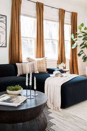 A living room with a dark blue sofa, a round coffee table, and a bookshelf.
