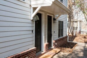 A two-story house with a front porch, a brick foundation, and a black front door.