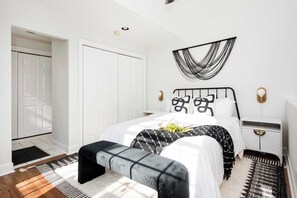 Una camera da letto moderna con un letto, comodini, una panca e un quadro appeso al muro.