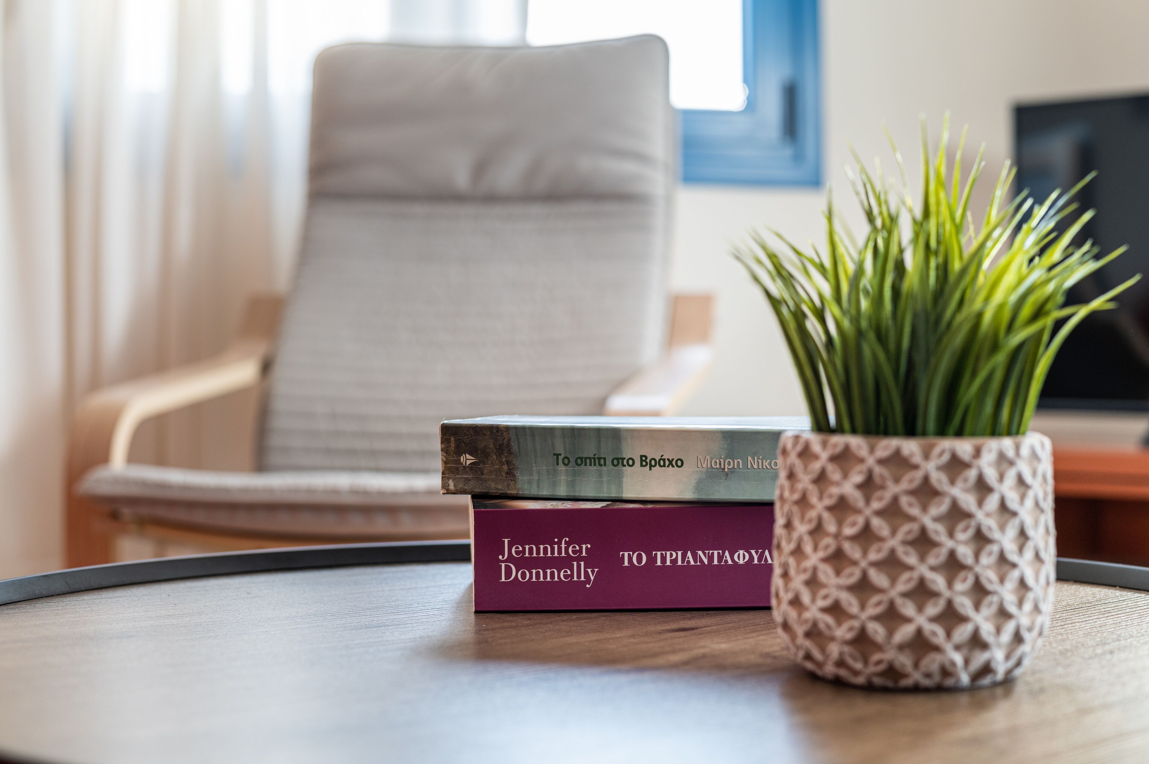 Une pile de livres sur une table, avec une plante en pot à côté.