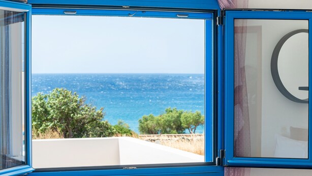 Un dormitorio con un ventanal que ofrece vistas al mar y al verdor.