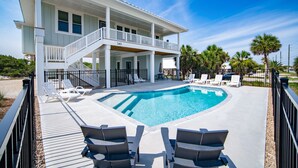 A two-story house with a swimming pool, outdoor seating, and palm trees. - Gulf Views, 4BR/4BA w/ Game Room, Private Pool w/ Heat, EV Charger (St. George Island)