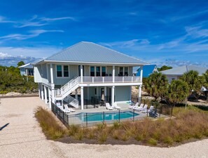 Une maison à deux étages avec un balcon, une piscine et une vue sur la plage.
