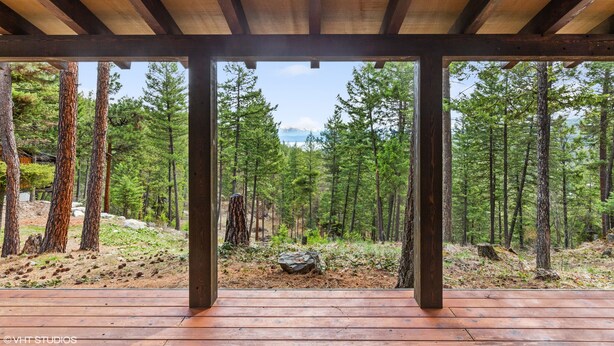 A wooden deck with a view of a forest and mountains.