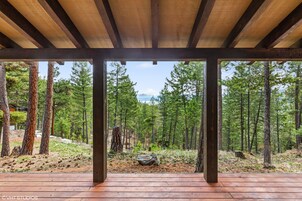 Une terrasse en bois offrant une vue sur une forêt et des montagnes.