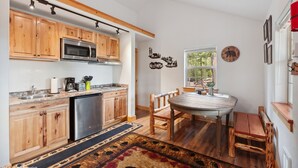 A modern kitchen with wooden cabinets, stainless steel appliances, and a dining area with a wooden table and chairs.