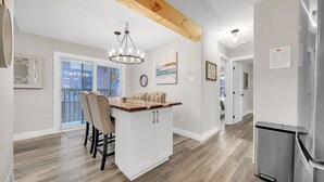 A modern kitchen with a wooden ceiling, white cabinetry, and a stainless steel refrigerator. - A bright & chic 2 bedroom urban apartment (Orangeville)