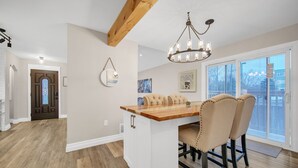 A kitchen with a wooden island, white cabinetry, and a chandelier. - A bright & chic 2 bedroom urban apartment (Orangeville)