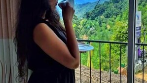 A person standing by a window with a view of a green landscape. - Dewy Arena Hotel (Ella)