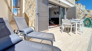 Um terraço com mesas ao ar livre, uma parede de pedra e vista para os arredores.
