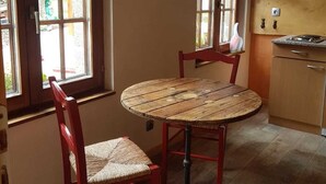 Uma cozinha com uma mesa de madeira redonda, duas cadeiras vermelhas e uma janela com vista para o exterior.
