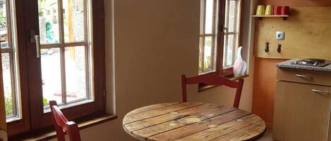 A kitchen with a round wooden table, two red chairs, and a window with a view of the outside.
