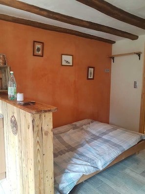Un dormitorio con cabecera de cama de madera, un escritorio pequeño de madera y una estantería en la pared.