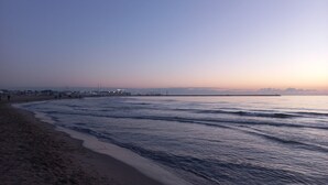 Een strand met een breed zandstrand en rustige golven.