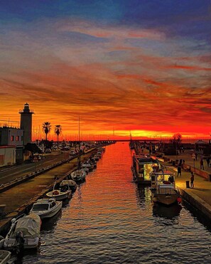A waterfront marina at sunset with boats docked along the waterway.