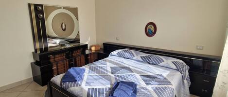 A bedroom with a bed, a dresser, a mirror, and a wall decoration.