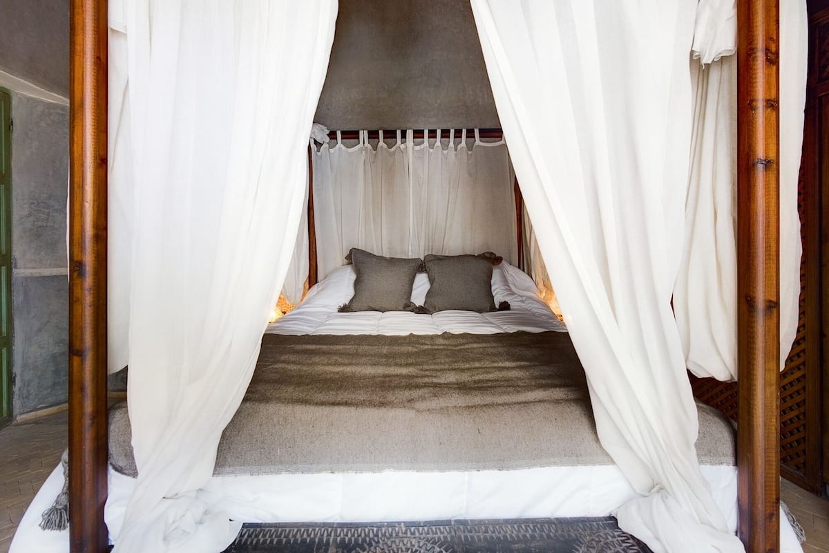 A bed with a canopy, pillows, and a textured blanket.